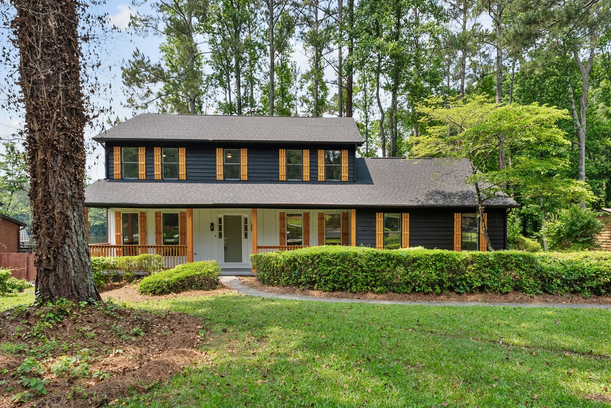 After: renovated front exterior with dark siding, cedar shutters and new landscaping — 5759 Albans Way, Lithonia GA