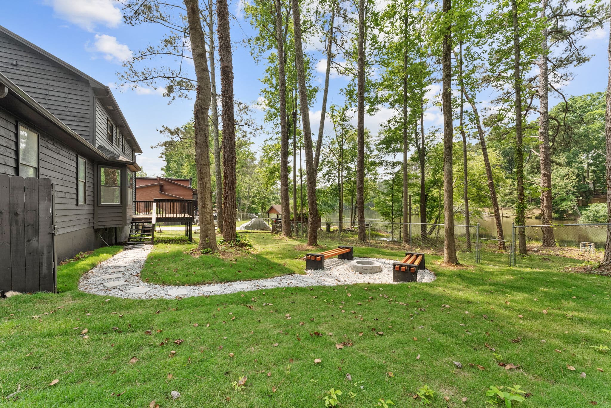 After: cleared back yard with stone path and fire pit overlooking the lake