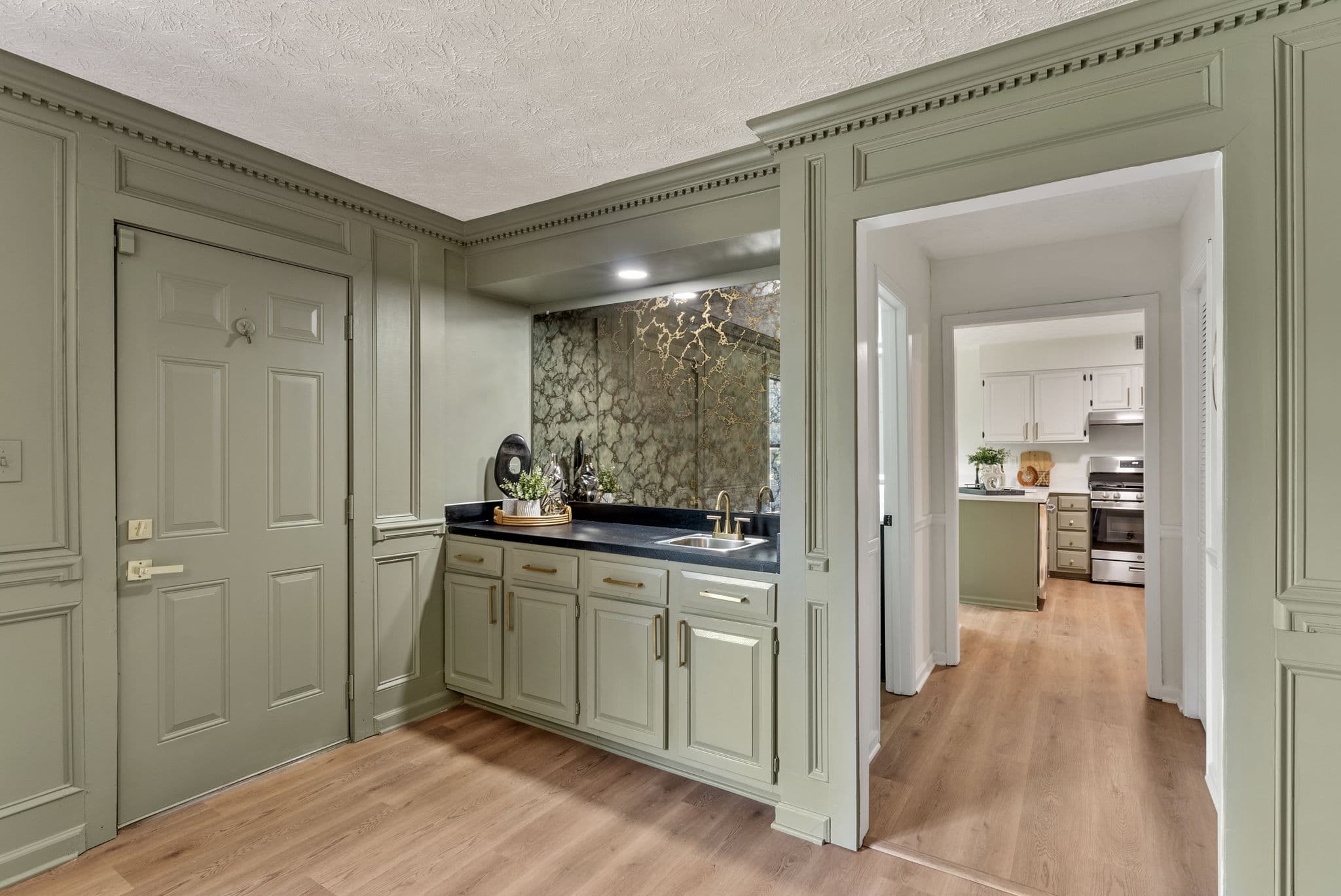 After: refinished wet bar with sage green cabinetry and brass hardware