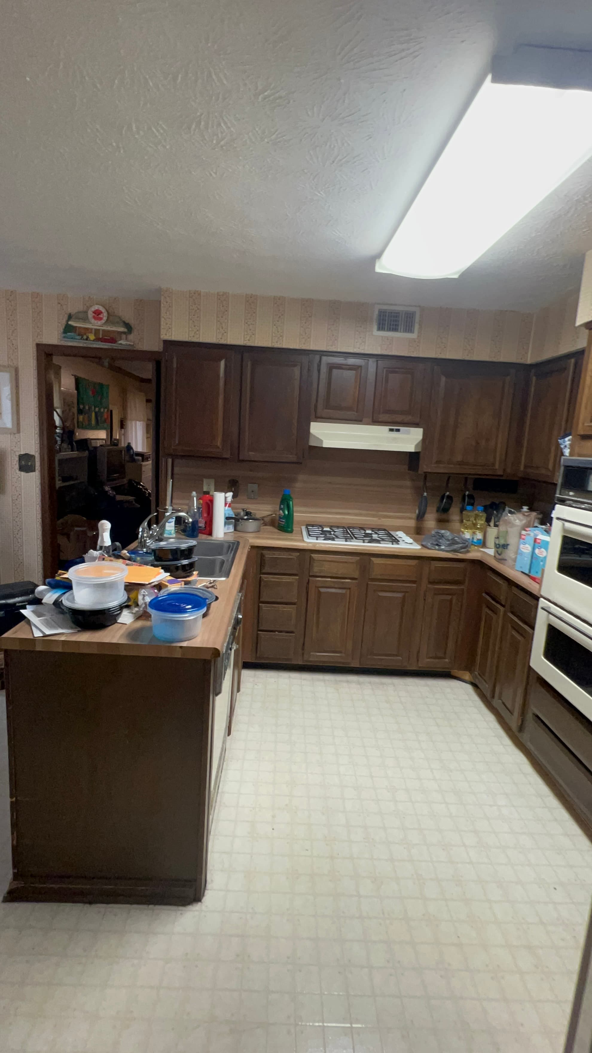 Before: dated kitchen with dark wood cabinets and vinyl floor